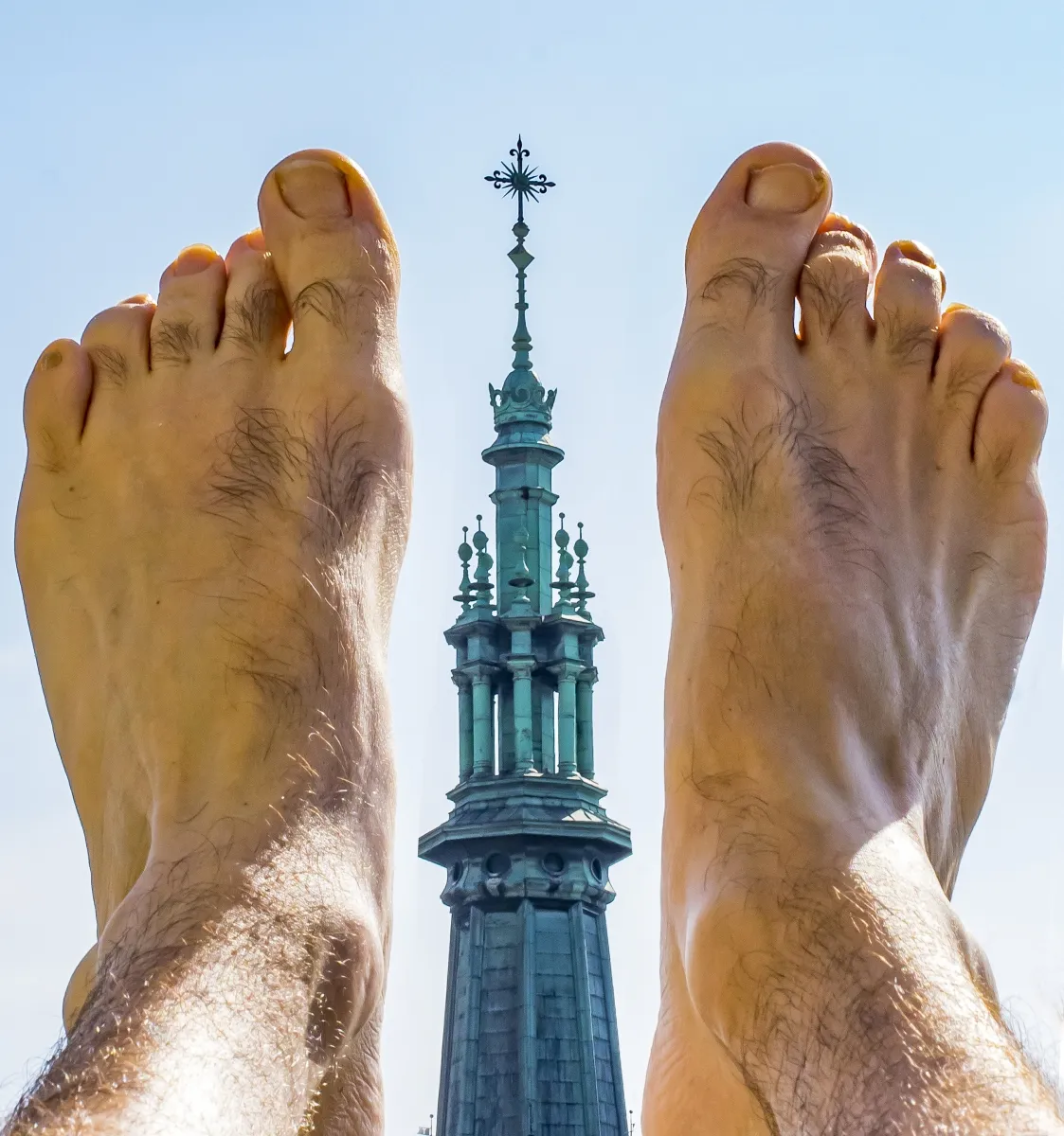 Bare feet framing a distant church tower topped with a cross